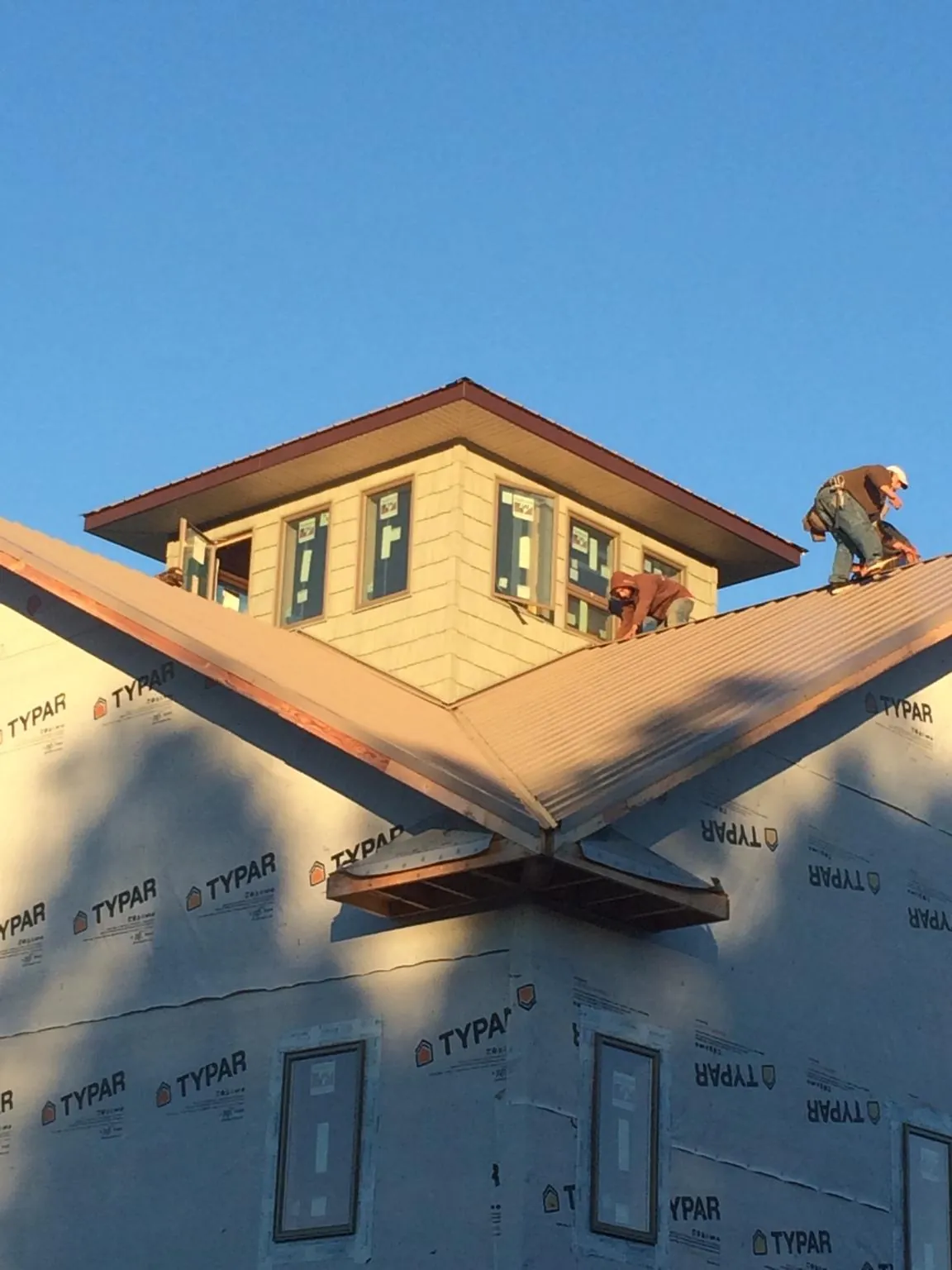 Roofers working around a rooftop cupola on a new metal roof at sunset — Roof Waterproofing in Brookhaven by Roofing Brothers
